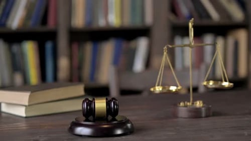 Waage aus Hammer und Goldmessing mit Büchern auf dem Richtertisch