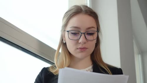 Young Concentrated Businesswoman in Glasses Working with Papers Document