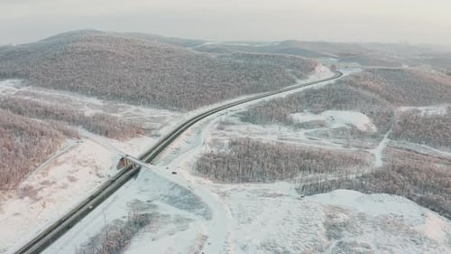 Approche de la route par Drone avec circulation dans les collines en hiver