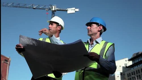 Architects Reviewing Blueprint on Construction Site