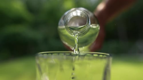 Pouring Fresh Water from a Glass Bottle