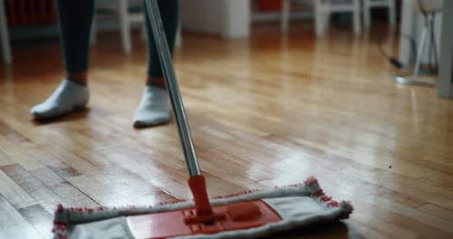 Person Mopping Wood Floor in Brightly Lit Room