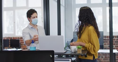 Man and woman wearing face masks working together in office