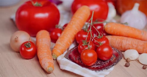 Close Up of Various Vegetables on Table Rotating. Fresh Cherry Tomatos, Carrot, Red Onion and Garlic