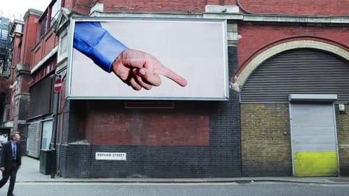 Man Observes Billboard Advertising in Urban Setting