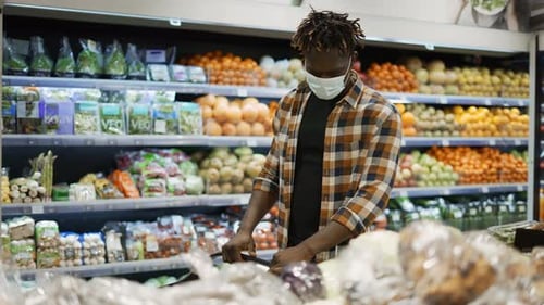 Man in Mask Push Cart escolhendo produtos na seção de produtos frescos