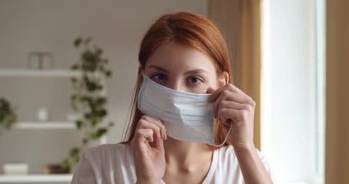 Woman Putting On Protective Surgical Mask Indoors