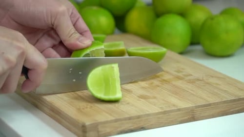 Cutting Fresh Green Limes on a Wooden Board