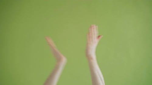 Close-up Shot of Hands Clapping Showing Thumbs-up Gesture on Green Background