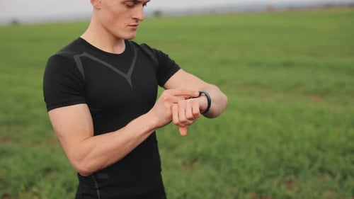 Athlete Checks Smart Watch in Rural Landscape