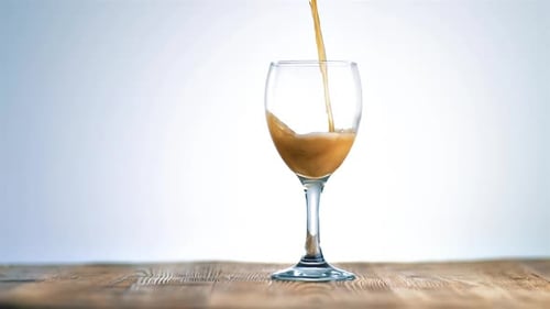 Brown Liquid Pouring Into a Clear Wine Glass