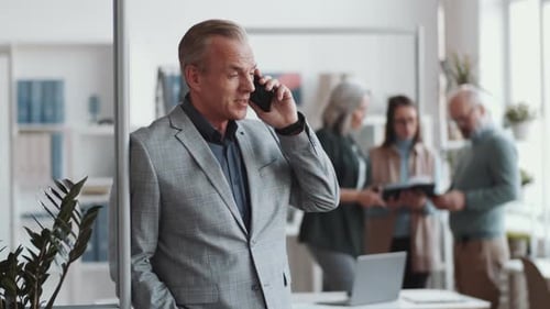 Cheerful Businessman Speaking on Mobile Phone in Office