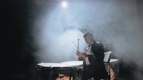 Man Playing Timpani Drums on Smoky Stage