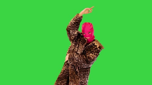 Aktives Mädchen in rosa Sturmhaube führt energetischen Tanz auf einem Greenscreen-Chroma-Key auf