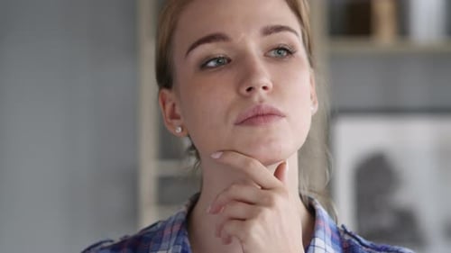 Young Woman Thoughtfully Gazing Upwards in Blue Shirt
