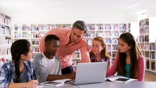 Professeur aidant des écoliers sur ordinateur portable