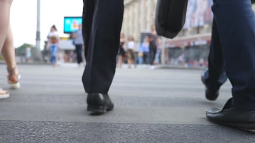Füße zweier Geschäftsleute überqueren die Straße in der Innenstadt. Beine männlicher Mitarbeiter, die auf einem Zebrastreifen in Big gehen
