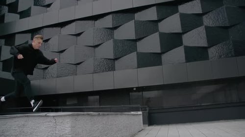 Junger Mann macht beim Modern City Free Running in Zeitlupe Flips and Jumps Parkour