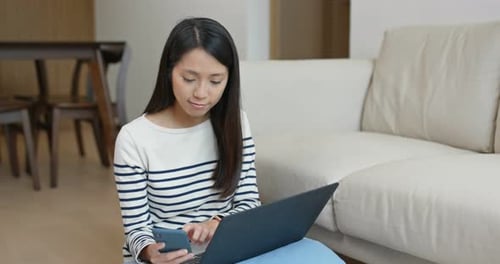 Woman Using Laptop and Smartphone Indoors