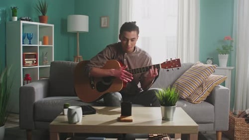 Young Adult Playing Guitar at Home