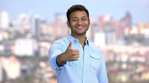 Young Adult Giving Thumbs Up with City Background