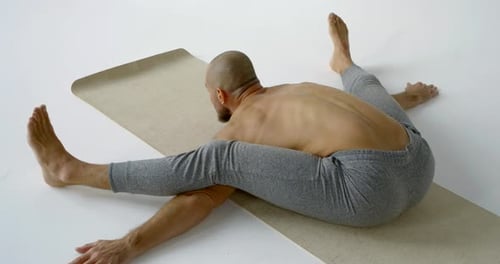 Man Stretching on Yoga Mat in Bright Studio
