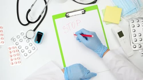 doctor's hand in a blue latex glove writes stop panic