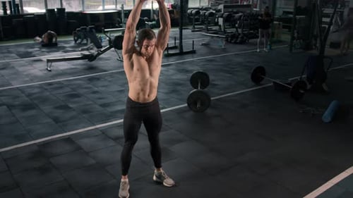Junger männlicher Athlet trainiert im Fitnessstudio mit Kurzhanteln, Crossfit, Ausdauertraining