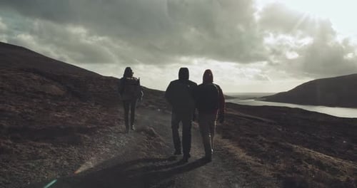 Three people walk together on hillside