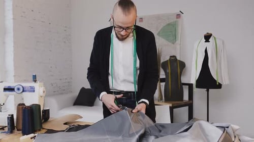 Tailor Cutting Gray Fabric in Stylish Workshop