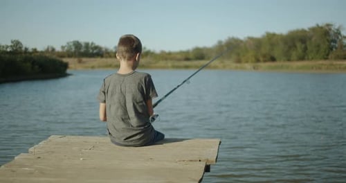 Small Boy Fisherman, Catching a Fish on a Rod on the Lake. Outdoors