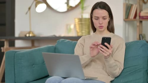Woman Using Phone and Laptop on Couch