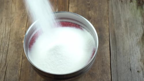 Sugar being poured into a stainless steel bowl
