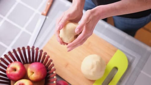 Woman Shaping Dough in Kitchen with Apples