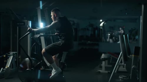 A Handsome Young Muscular Sportsman is Doing Exercise on a Fitness Machine in the Gym
