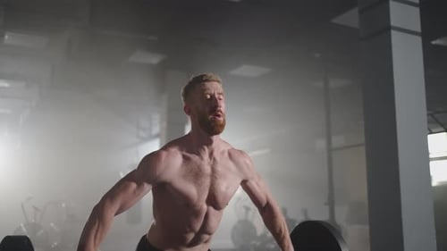 A Young Male Weightlifter Lifts a Heavy Barbell Over His Head Performing a Jerk