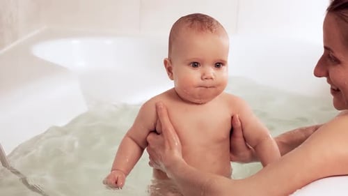 Infant Enjoying Bath Time with Adult in Tub