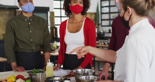 Chef Instructs Masked Adults in Bright Kitchen