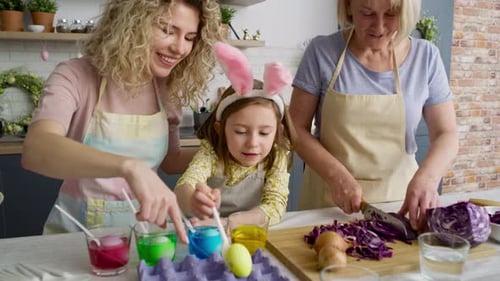 Vídeo de tres generaciones de mujeres preparando huevos de Pascua juntas.