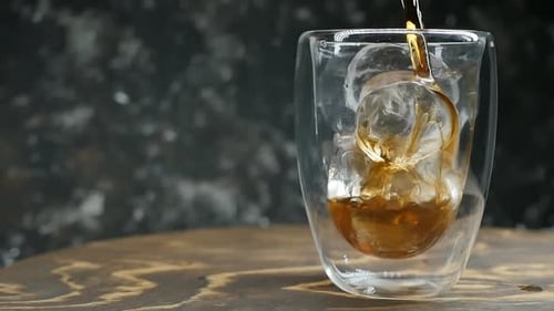 Dark Liquid Being Poured into Clear Glass with Ice