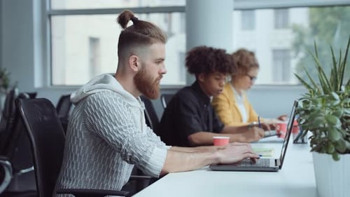 Hipster barbu travaillant sur un ordinateur portable au bureau