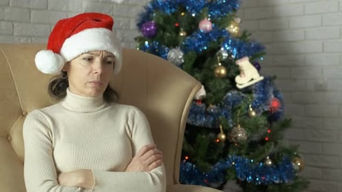 Woman with Santa Hat Sitting Cross Armed in Chair