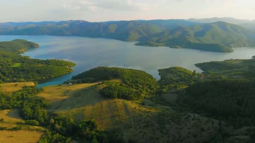 Flying toward a lake with a horizon view of a wrinkled mountains.