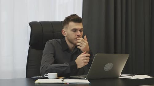 Man sitting in modern office and looking on laptop screen. Business corporate concept