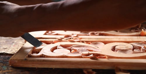 Wood Carver Working Intricately with Chisel on Design
