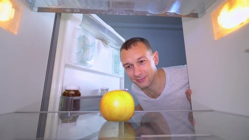 Man Checks Single Apple in Refrigerator