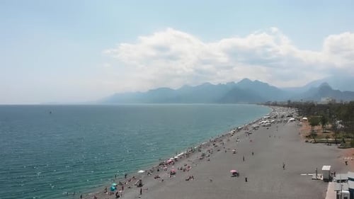 Beautiful sea coastline with wide pebble beach, calm sea and mountains on background.
