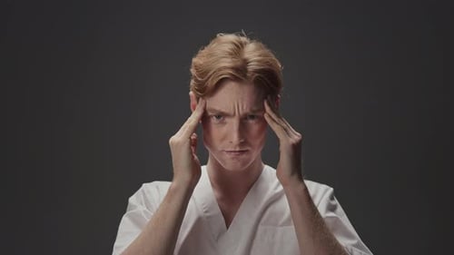 Red-Haired Young Adult With Hands on Temples