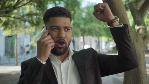 Man Receives Good News on Phone in City Park