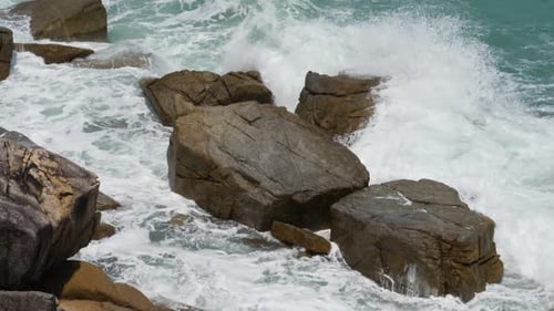 Meerwasser und Riesenwellen krachen an Rocky Cliff mit Spritzern und weißem Schaum